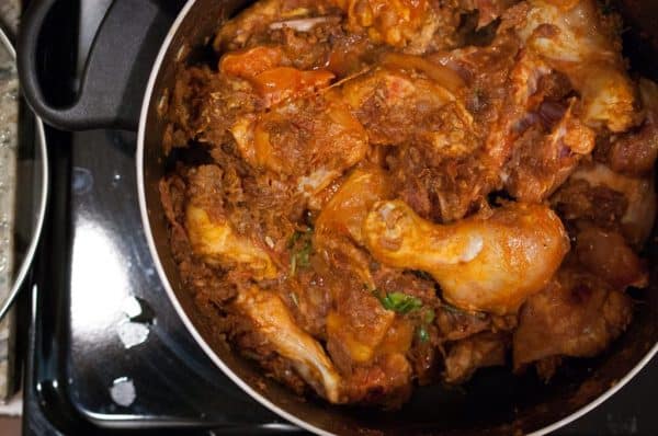 Marinated chicken mixed with rich masala in a pot for Nadan Kozhi Roast recipe.