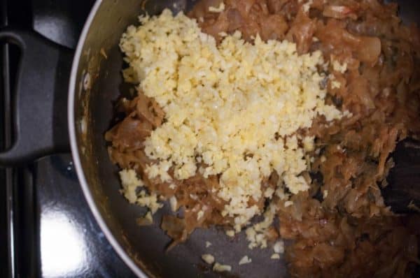 Adding ginger-garlic paste to the sautéed base for Kozhi Roast.