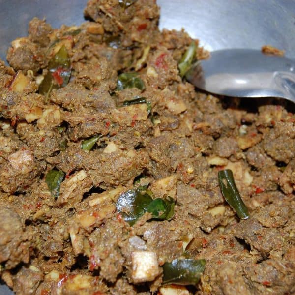 Cooked beef added to sautéed coconut and curry leaves for Beef Ularthiyathu preparation.