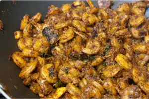 Chemmeen roasted till dark with thick masala coating in a nonstick pan.