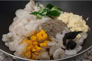 Raw prawns mixed with turmeric, crushed garlic, pepper, curry leaves, and kokum for Kerala Style Konchu Roast.