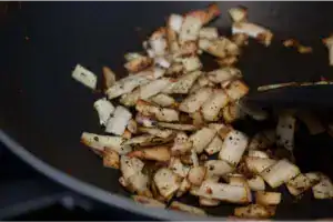 Roasted coconut pieces (thengakothu) being browned in a pan for chemeen ullathiyathu.