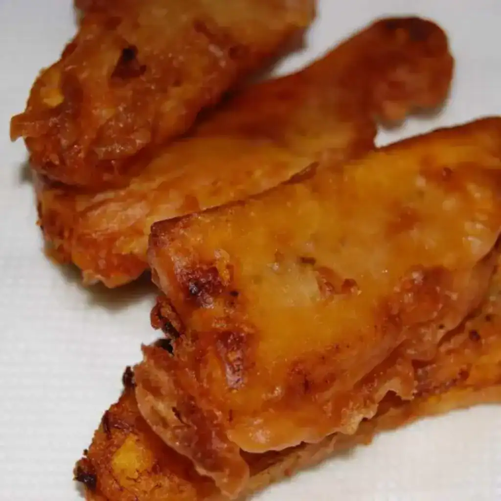Crispy pazham pori served on a white plate, golden and unevenly shaped just like homemade ones.
