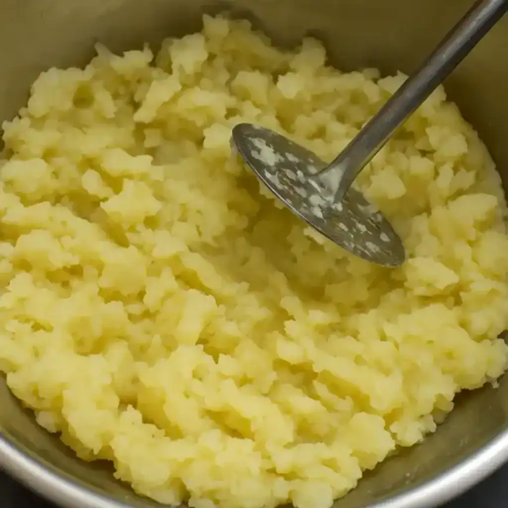 Tapioca mashed evenly using a steel masher, the core step for Kappa Erachi preparation.