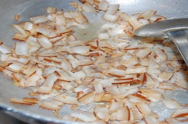 Coconut pieces frying in hot oil until golden brown for Kerala pork fry.