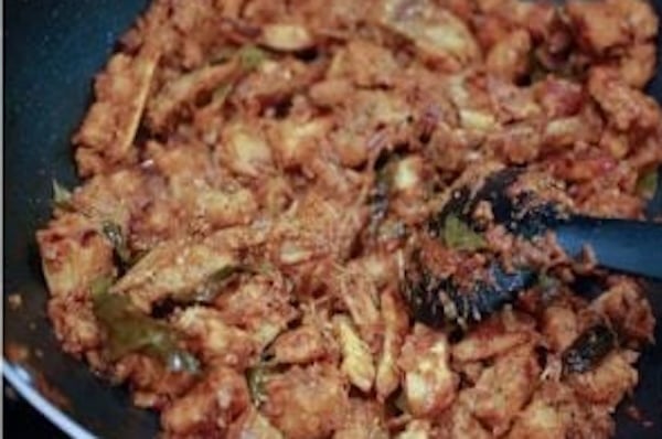Roasting cooked pork with coconut until dark and caramelized for Nadan Pork Ularthiyathu.