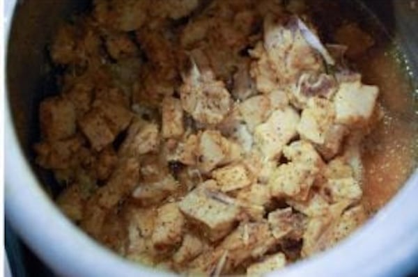 Pork cubes cooking with Kerala spices in a pressure cooker until tender.