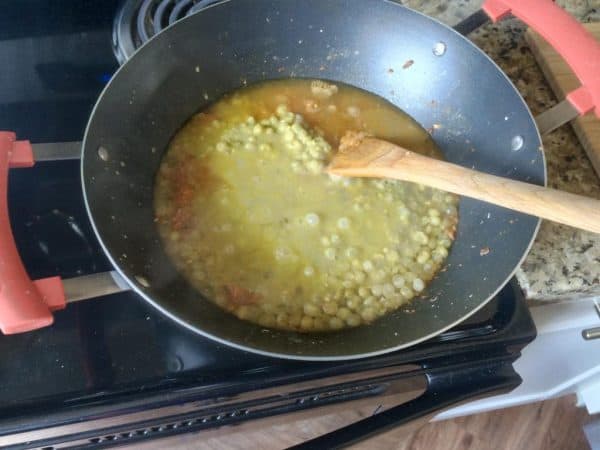 Pressure-cooked peas added into roasted masala with water in a kadai.