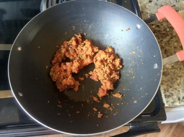 Roasted onion base mixed with chopped tomato and spices in a kadai for Kerala Green Peas Curry.
