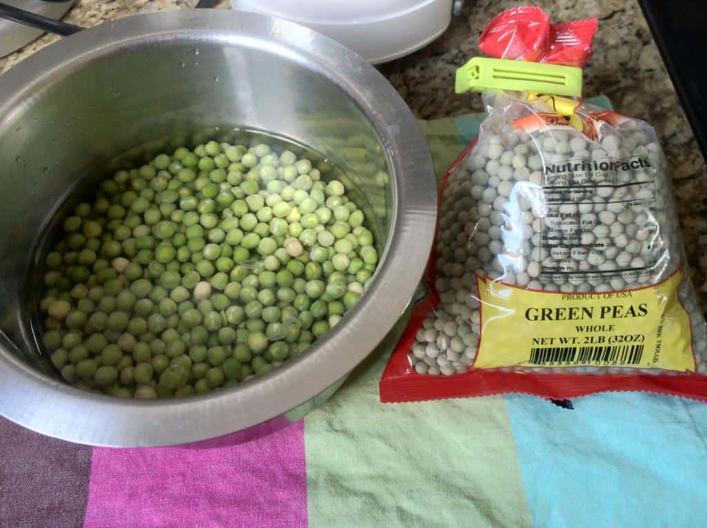 Dried green peas soaked overnight in a steel bowl beside a packet of whole peas for cooking Green Peas Curry preparation.