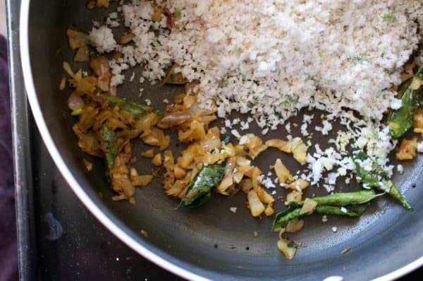 Crushed coconut mixture is added to the sautéed mixture in the pan for making payar thoran.