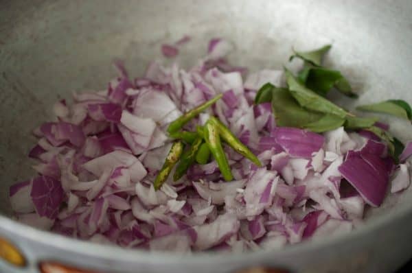 Chopped onions, green chilies, and curry leaves sautéing in a pan for Kerala Kadala Curry.