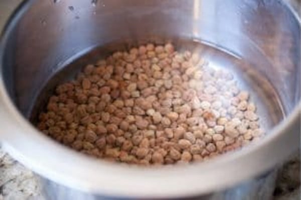 Brown chickpeas soaked in water overnight in a steel bowl for Kadala Curry preparation.