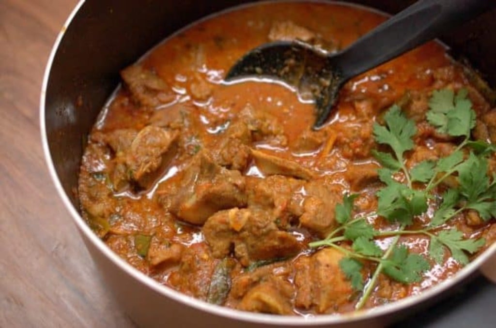 Nadan aadu curry is cooked and served with coriander garnish in a nonstick pot.