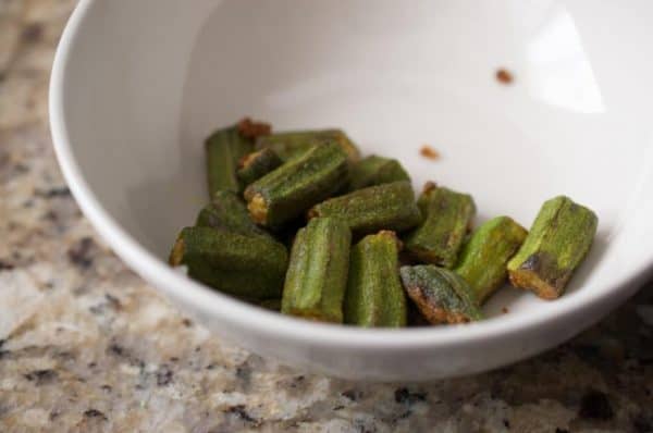 Lady’s finger pieces shallow fried with salt in a white bowl, kept aside for adding into Kerala sambar.
