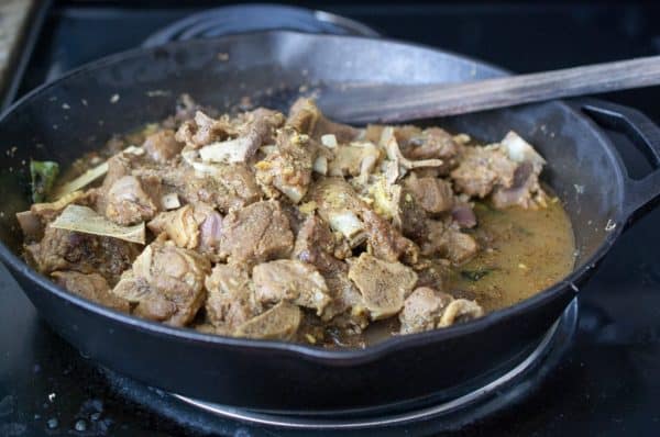 Cooked Mutton simmering in a rich, spice-infused gravy in a cast-iron pan.
