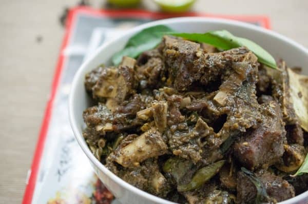 Nadan Mutton Pepper Fry, served in a white bowl with fresh curry leaves on top.