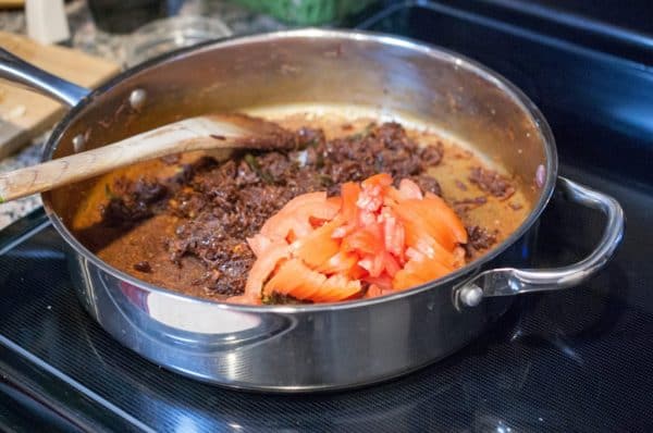 Chopped tomatoes are added to roasted onion masala while making konchu masala.
