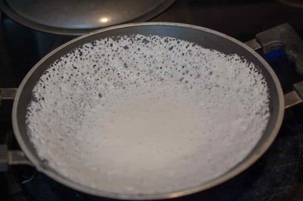 Kerala Style Appam cooking in appachatti with lacy crisp edge and soft center.