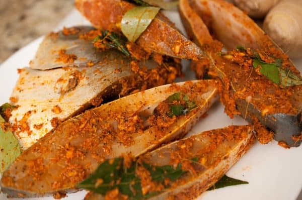 Fish marinated with masala and curry leaves, resting on plate for Meen Varuthathu.