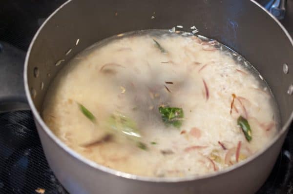 Water is added to sautéed rice with whole spices and curry leaves while making Kerala ghee rice.