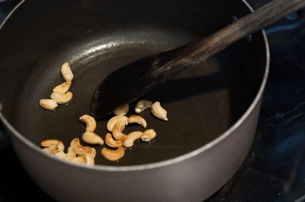 Cashews being roasted in ghee in a thick-bottomed pan for garnishing Kerala ghee rice.