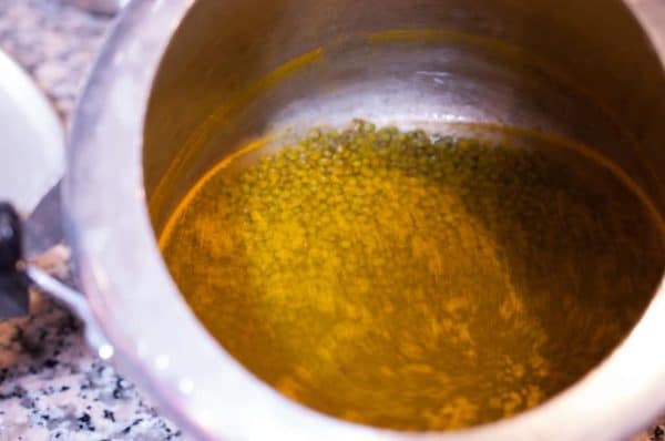 Cooked green gram/moong bean with turmeric and salt in a pressure cooker for Cherupayar Thoran preparation.