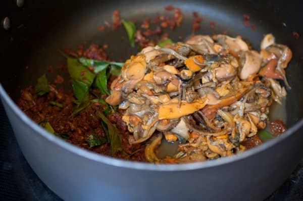 Cooked kallumakkaya added to the roasted masala in a wide pan with curry leaves.
