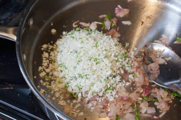 Crushed coconut mix is added to the tempered onion in the pan.