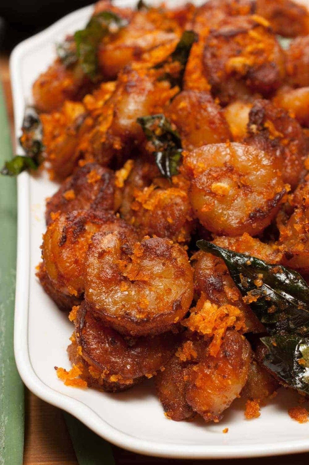 Kerala-style prawns fry with sautéed coconut and curry leaves, served on a white plate.