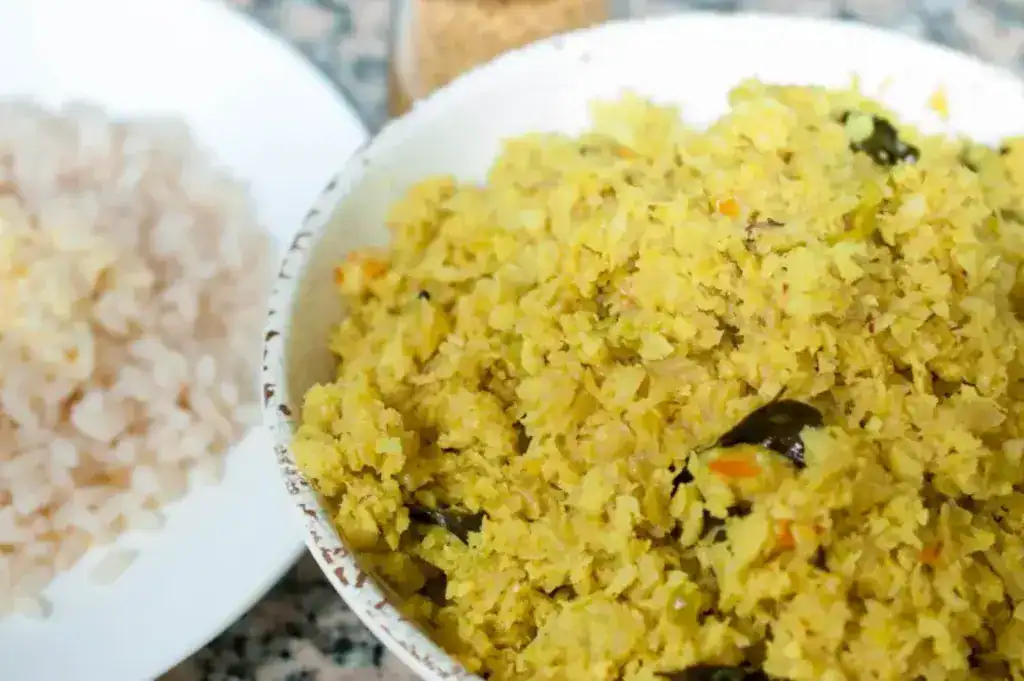 Kerala style cabbage thoran served in a white bowl with Kerala red rice on the side.