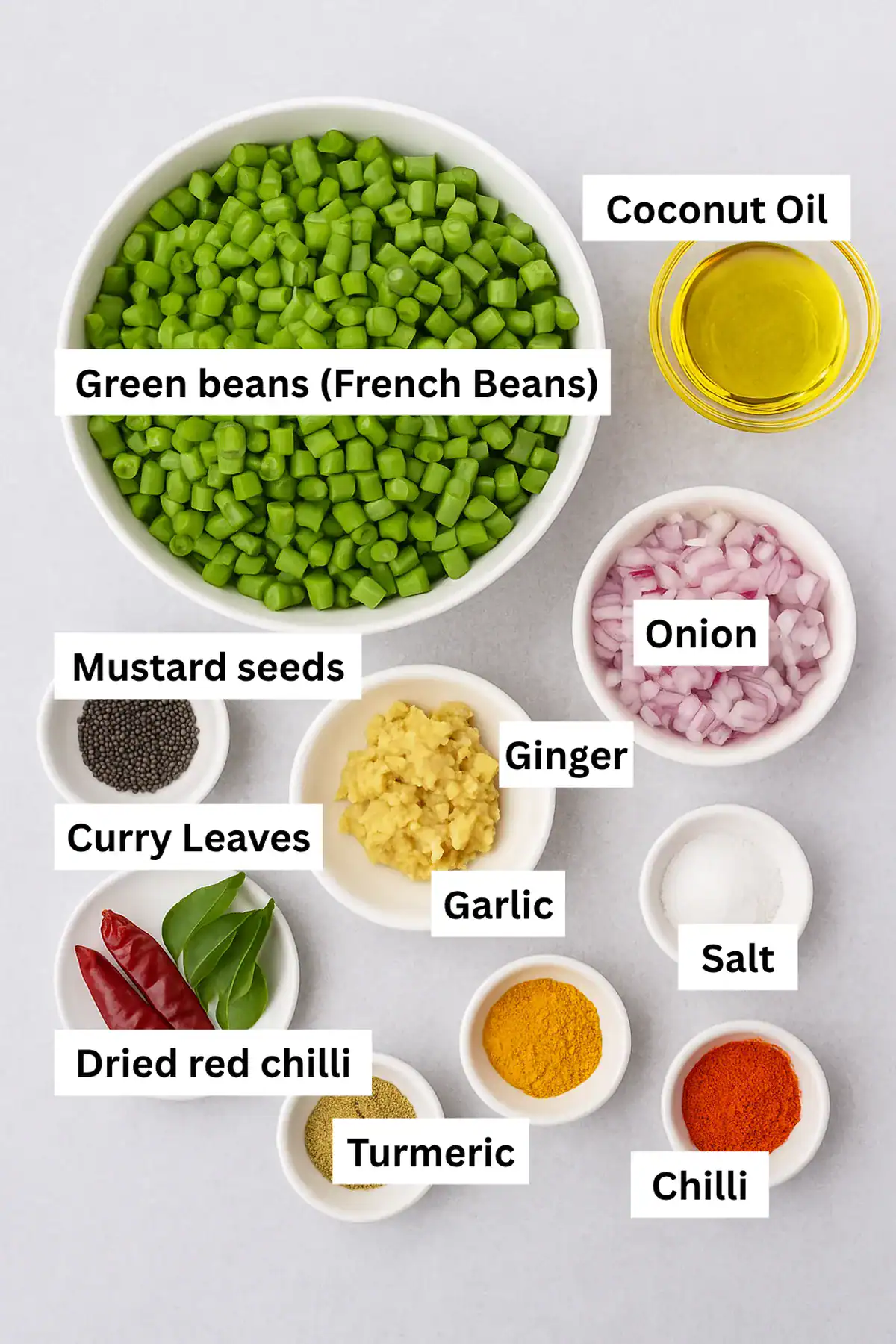 Payar Mezhukkupuratti ingredients on grey background with beans, onion, garlic, ginger, mustard, curry leaves, chilli, oil.