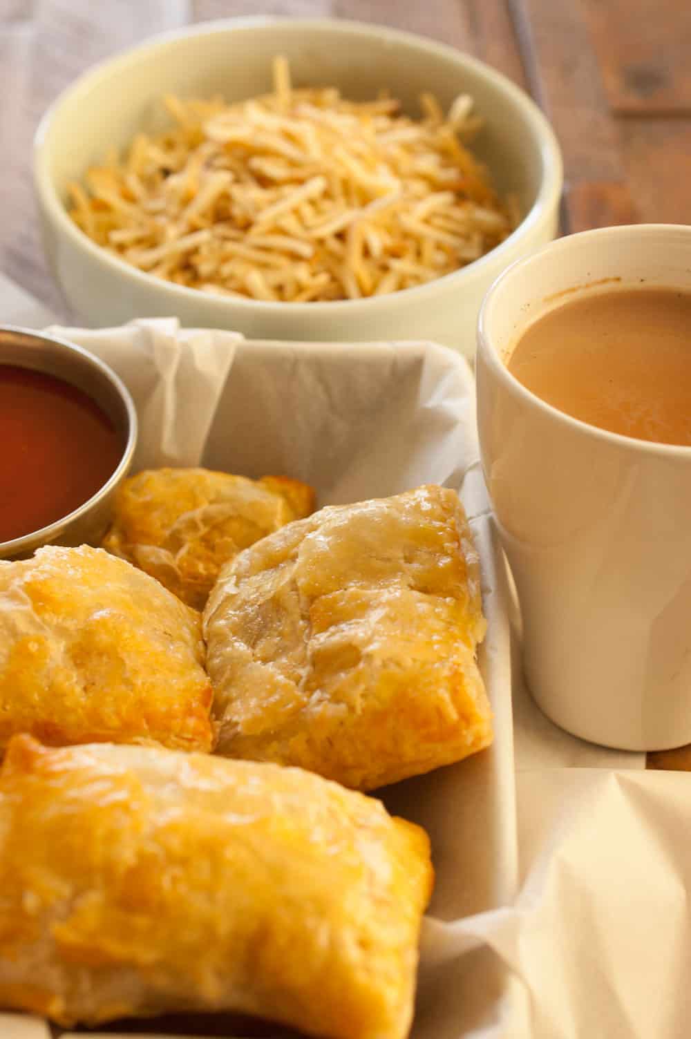 This is an image of Indian style chicken puffs. Tea, tomato ketchup and tapioca chips on the side 