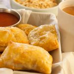 This is an image of indian chicken puffs with tea on the side, ketchup as dipping and some tapioca chips