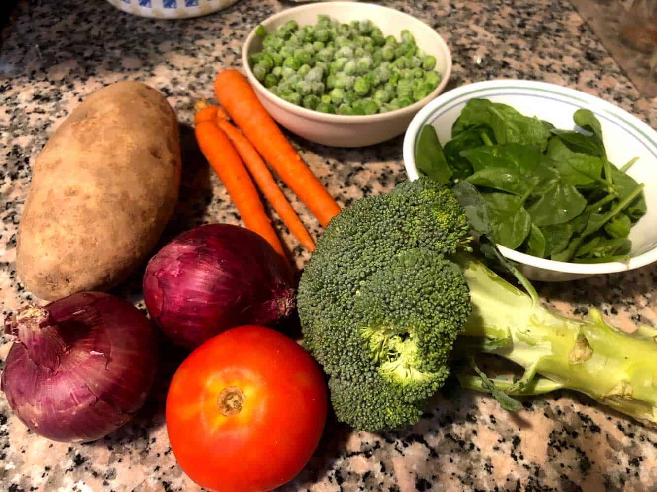 Ingredients of Mixed vegetable curry - potato, carrot, frozen green peas, spinach, broccoli, onion and tomato
