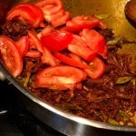 Adding sliced tomato into sauteed onion and masala mix