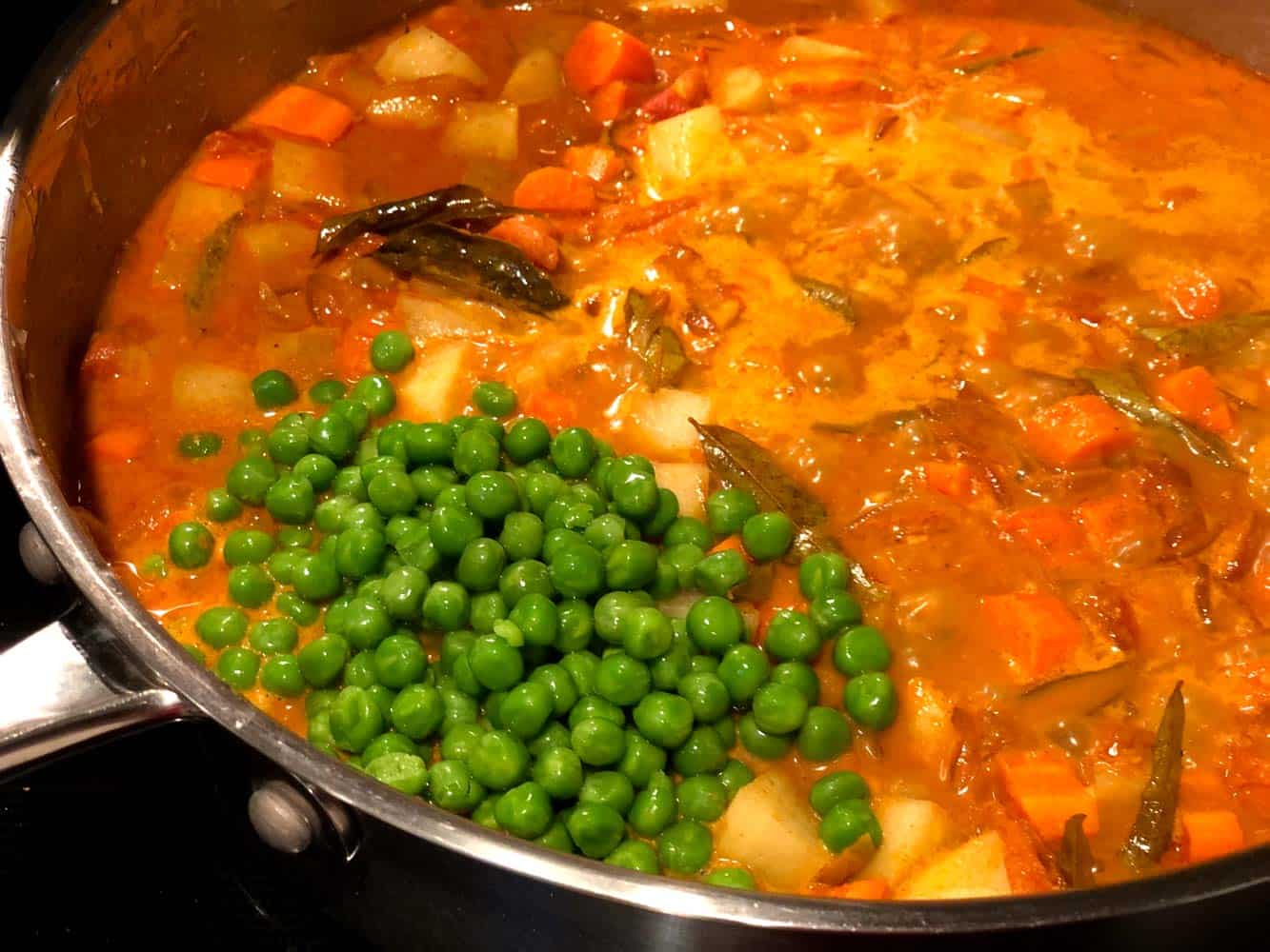 Adding frozen green peas into the gravy